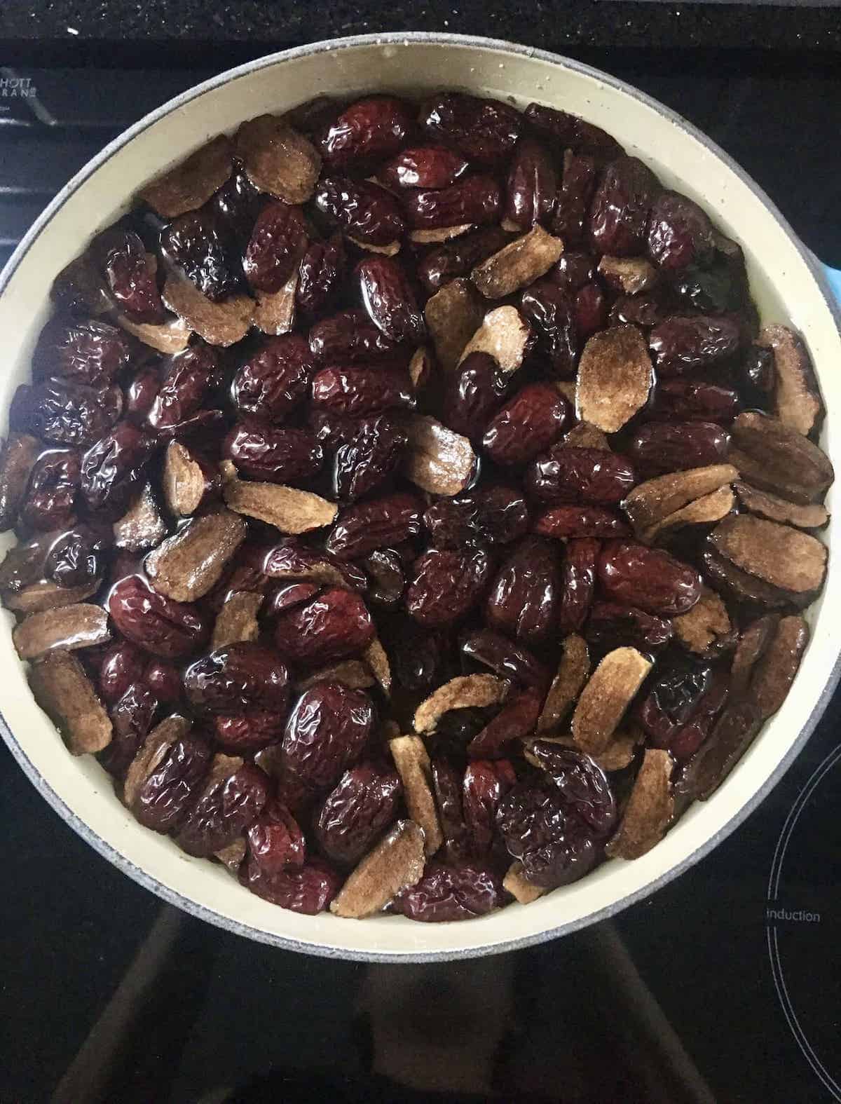 A huge Le Creuset pot filled with cut up jujubes and water.