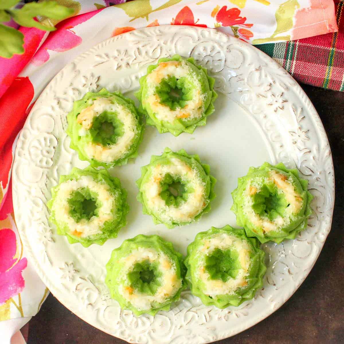 7 green-coloured pandan kueh on a plate.