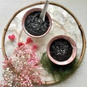2 bowls of Chinese black sesame tong sui next to pink flowers.