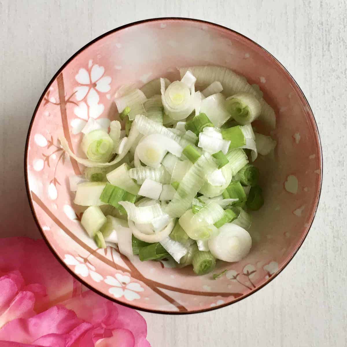 A bowl of sliced white spring onions (the bottom part of the stalk).