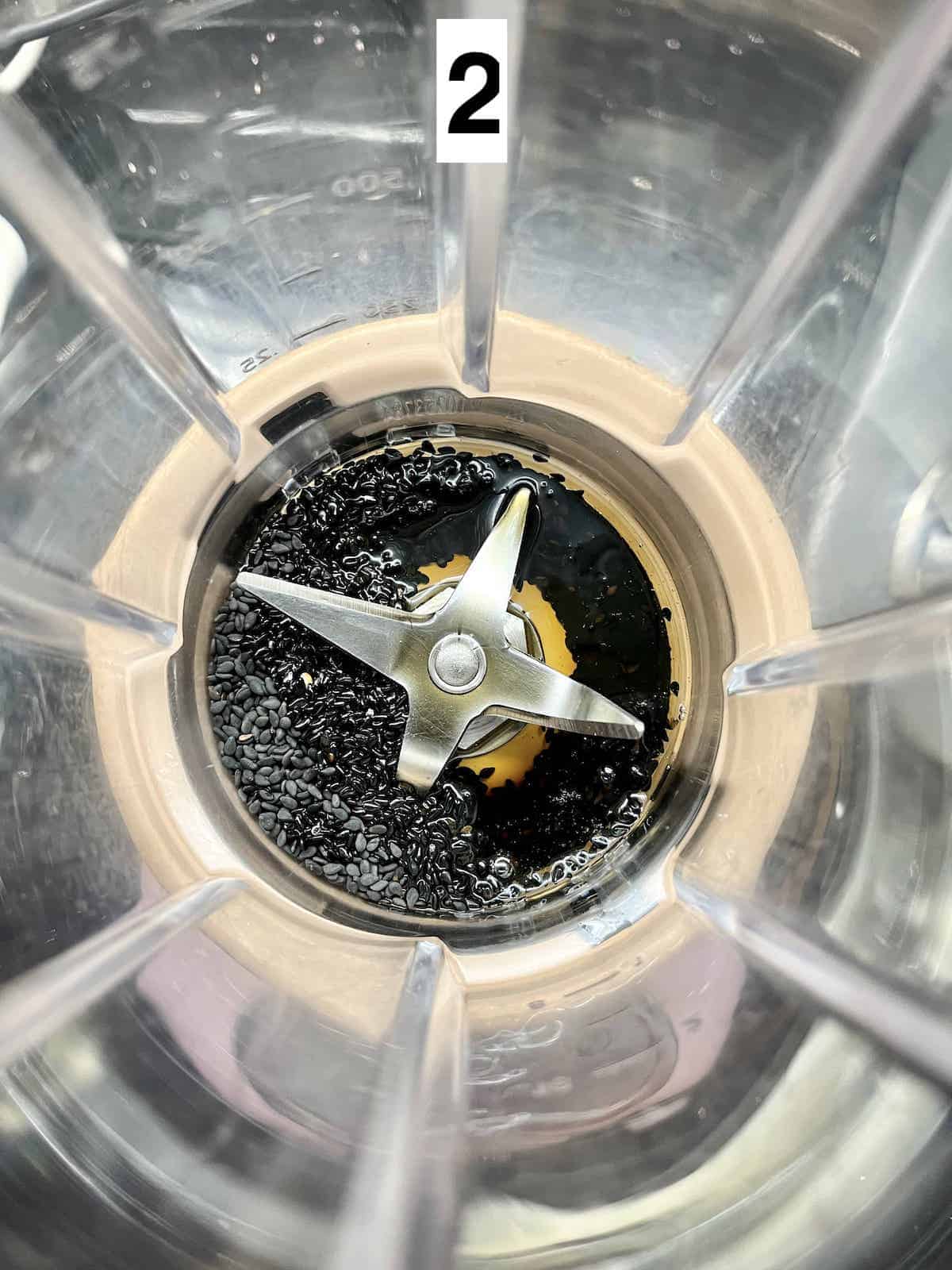 Close-up of the inside of a blender with black sesame seeds and sesame oil inside.