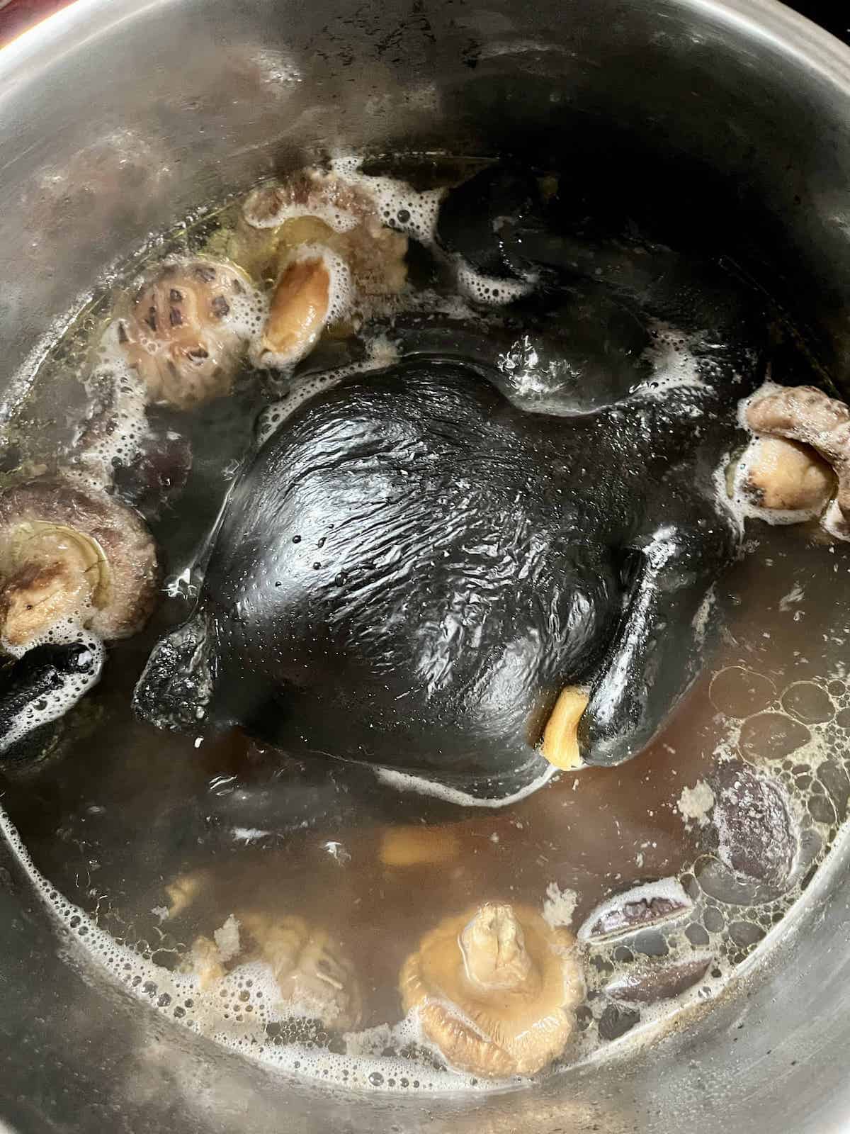 Overheat shot of a pot with a black chicken, mushrooms and jujubes.