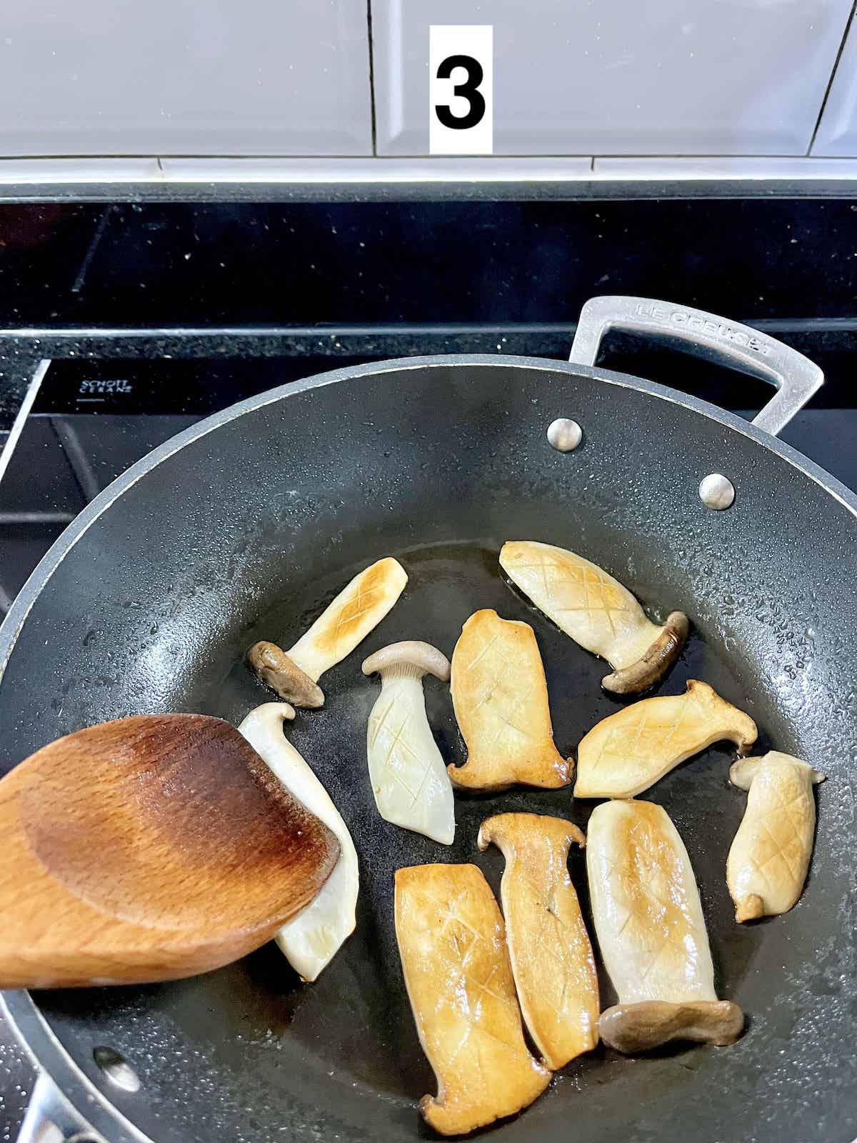 Pressing down eryngii mushrooms when cooking in a pan.