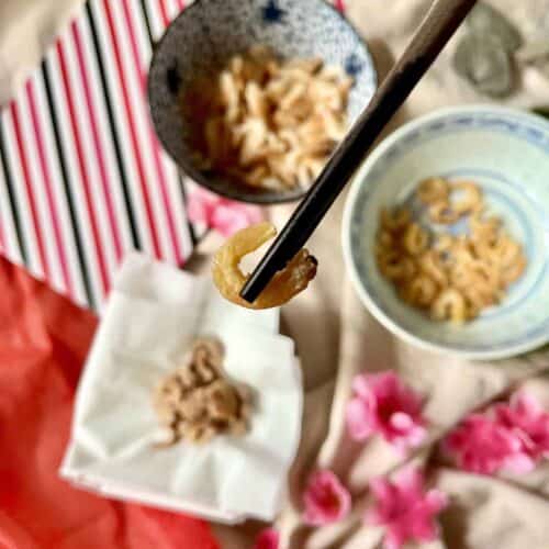 A dried shrimp held up by a pair of chopsticks.