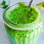 Bright green avocado chutney in a glass jar.