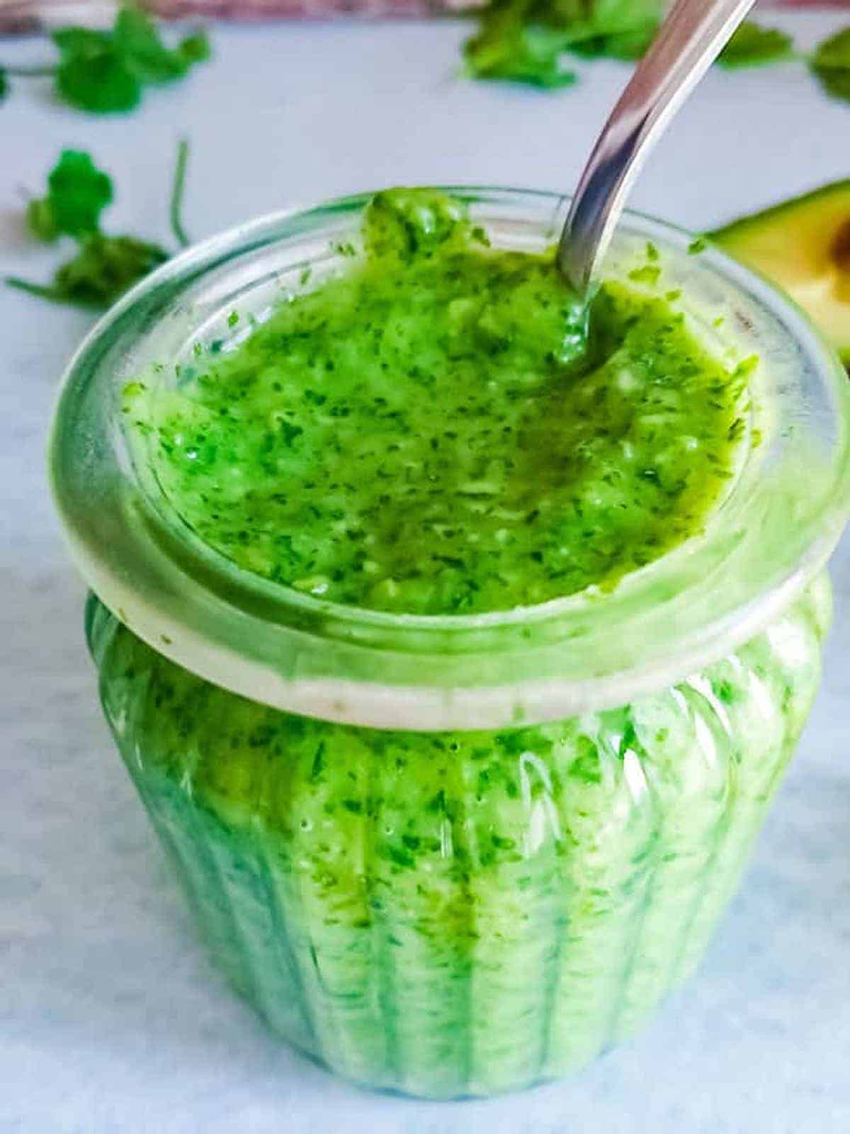 Bright green avocado chutney in a glass jar.