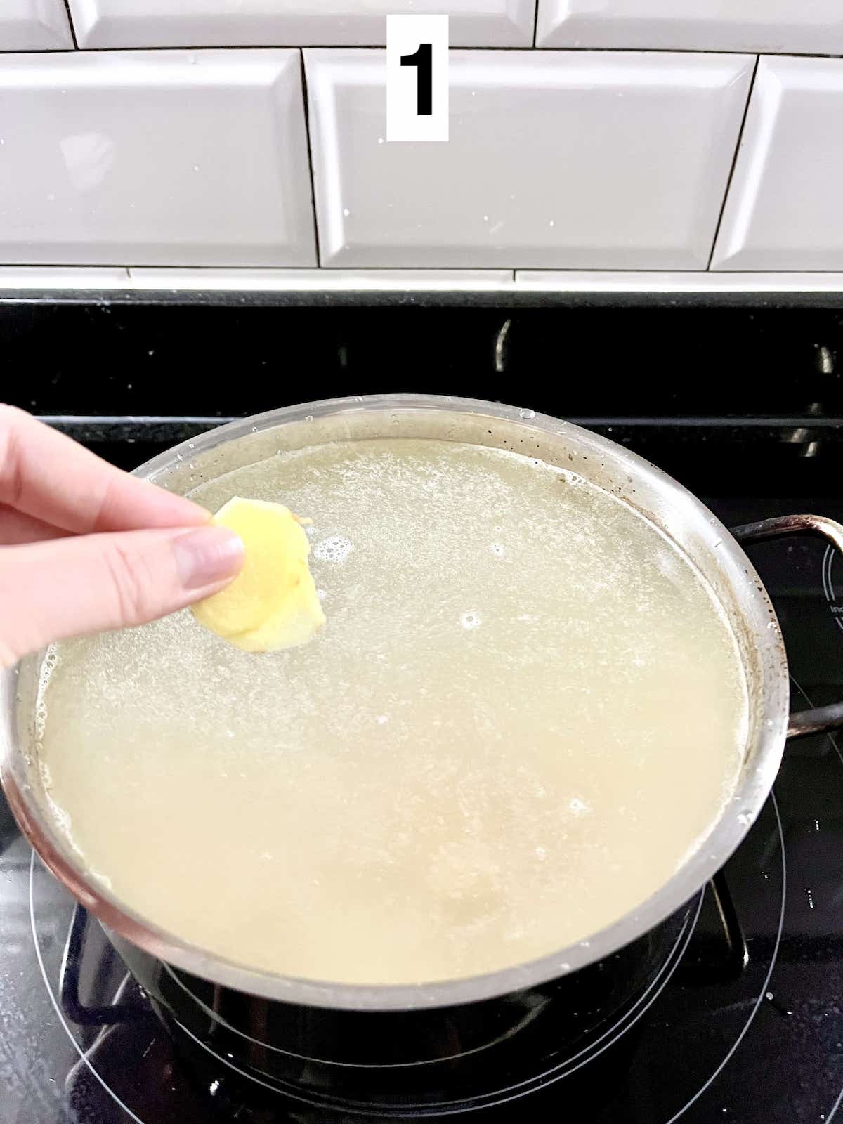 Adding slices of ginger to a pot of abalone rice porridge.