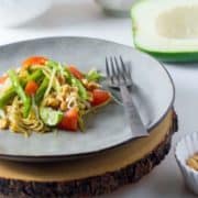 Side view of a plate of green papaya salad with tomatoes.