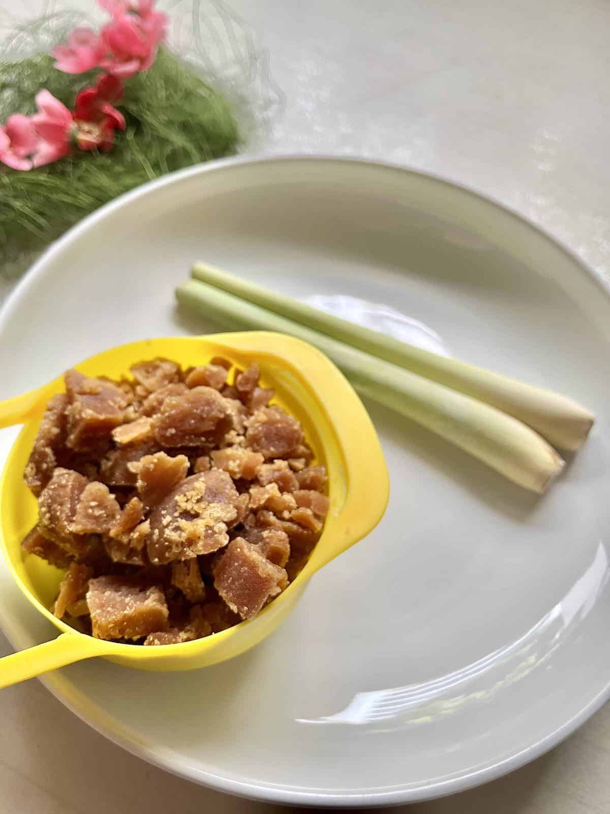 Gula Melaka sugar and lemongrass on a white plate.