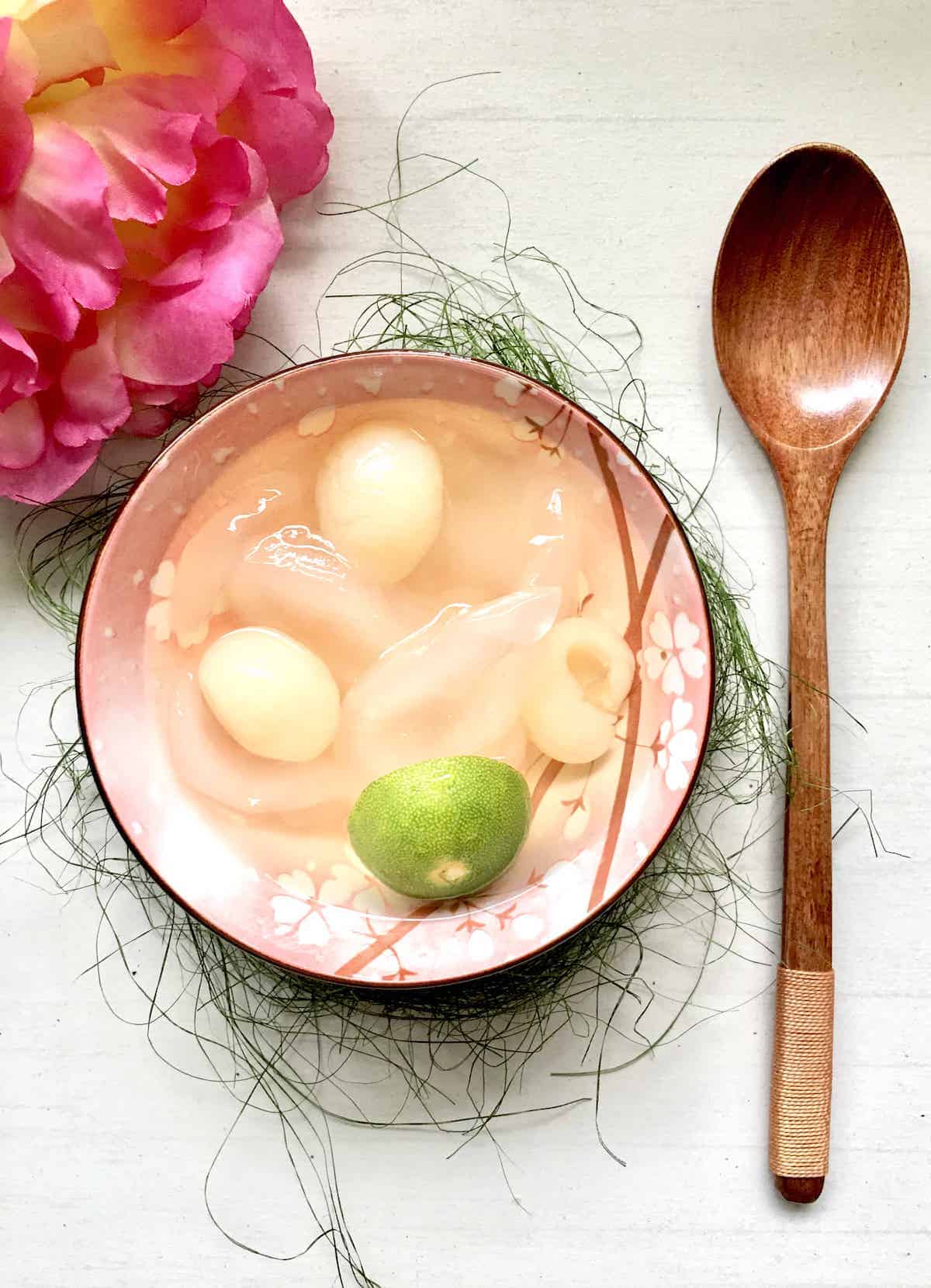 A bowl of sea coconut dessert with canned longan with calamansi lime.