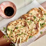 Crispy and flaky pan fried scallion pancakes on parchment paper.
