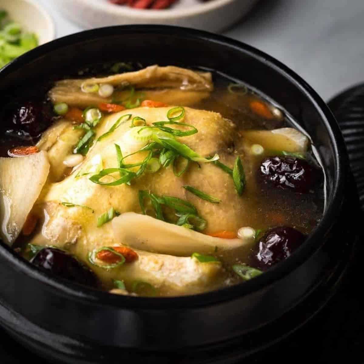 Close-up of red date chicken soup in a black pot.