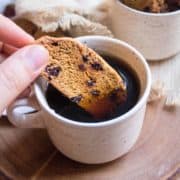 Someone dunking goji berry biscotti in a cup of tea.