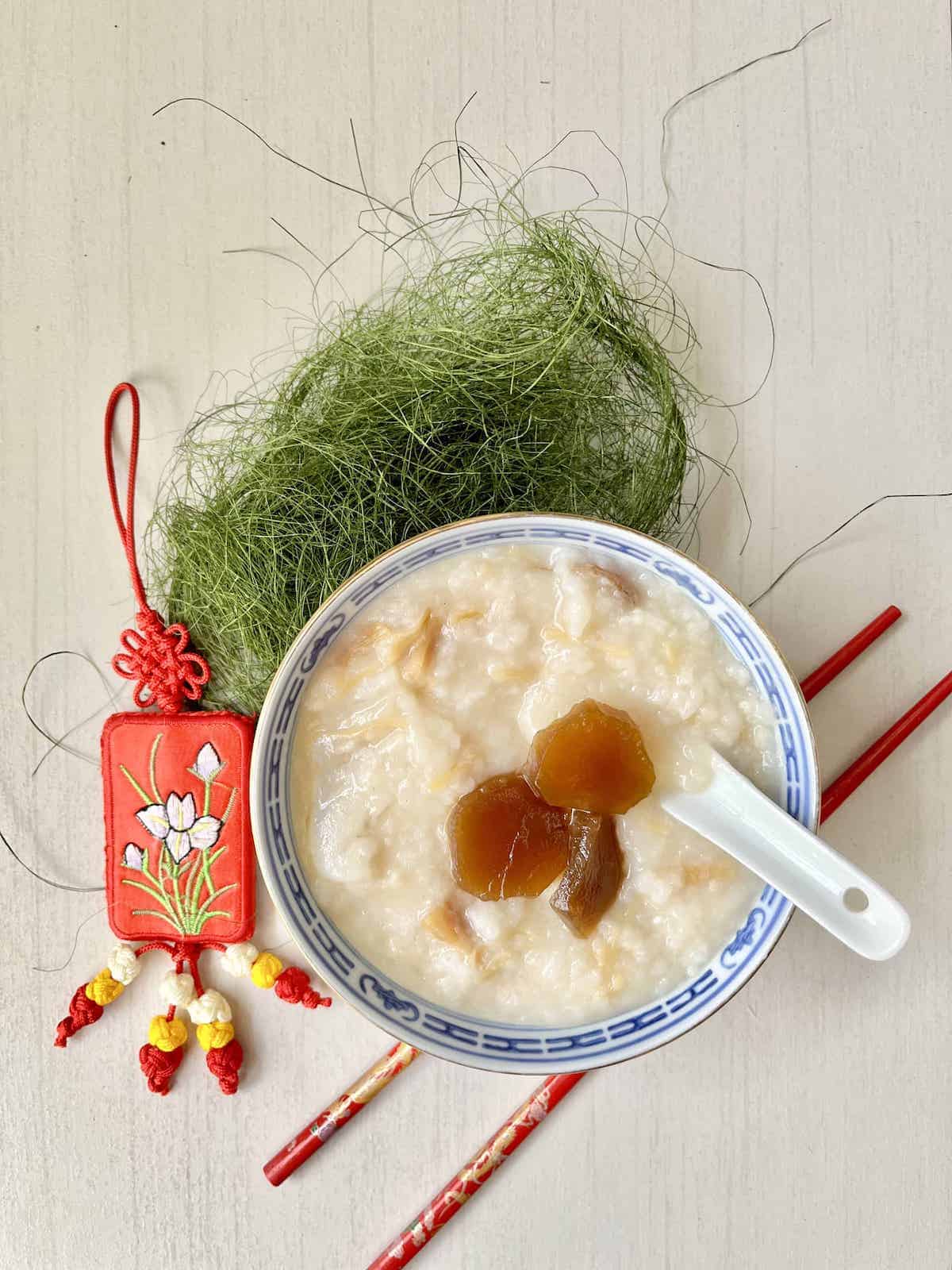 A bowl of Cantonese scallop porridge with pickled lettuce on top.