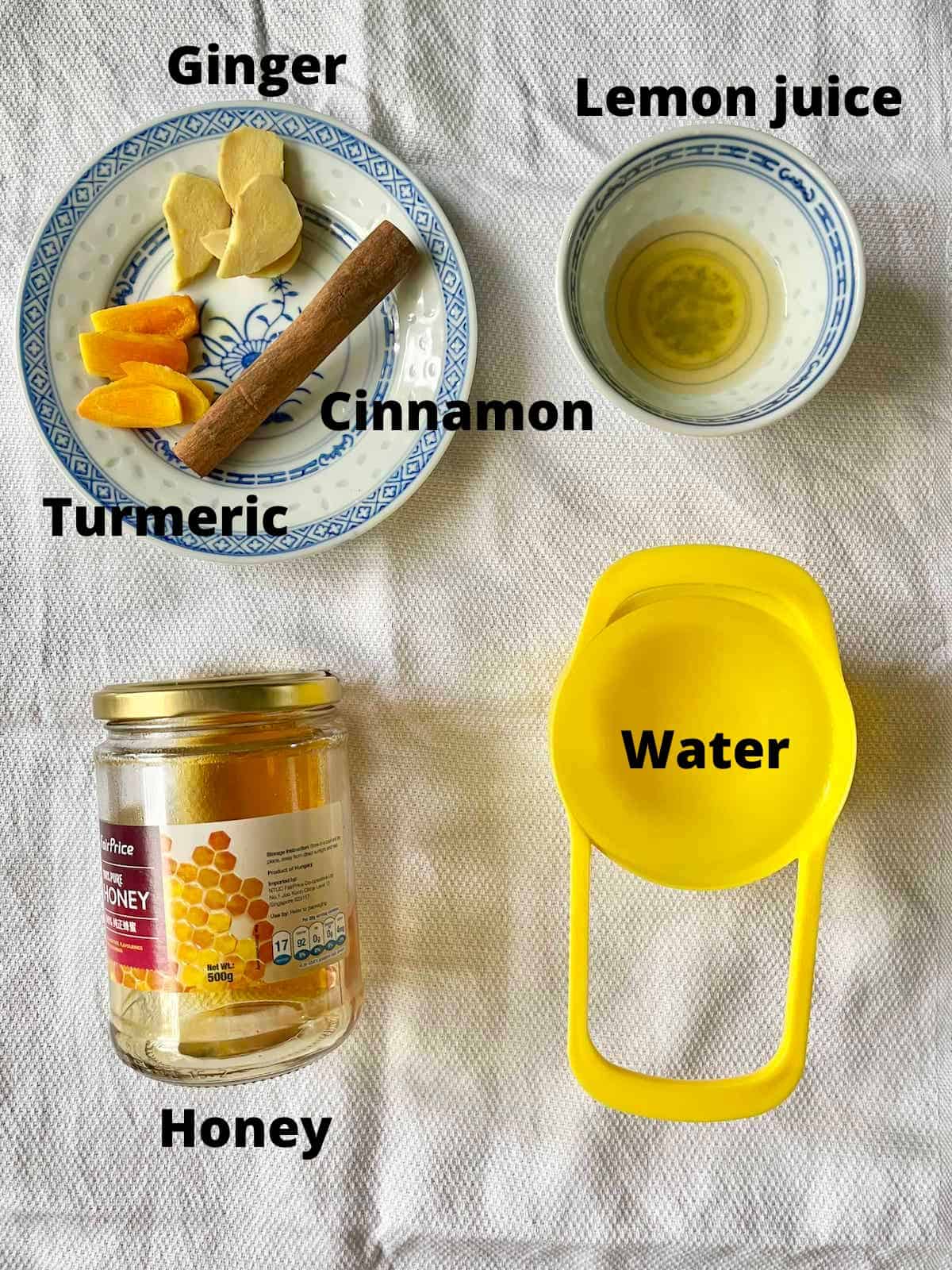 The ingredients needed for turmeric cinnamon lemon ginger honey tea on a white tablecloth.