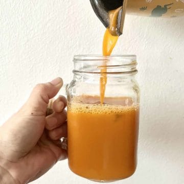 Guava black tea being poured into a glass mug.