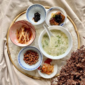 A bowl of rice porridge with 5 side dishes.