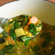 A close-up of lentil soup being scooped out of a pot.