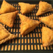 8 golden samosas on a tray.