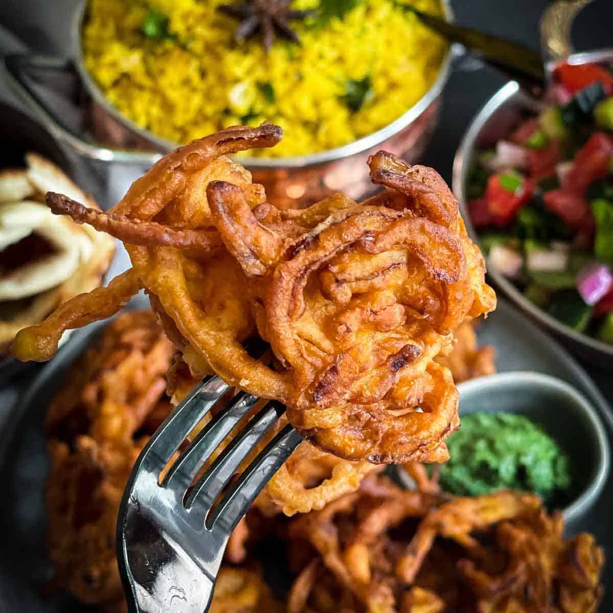 A close-up of a fork inserted into onion bhaji.