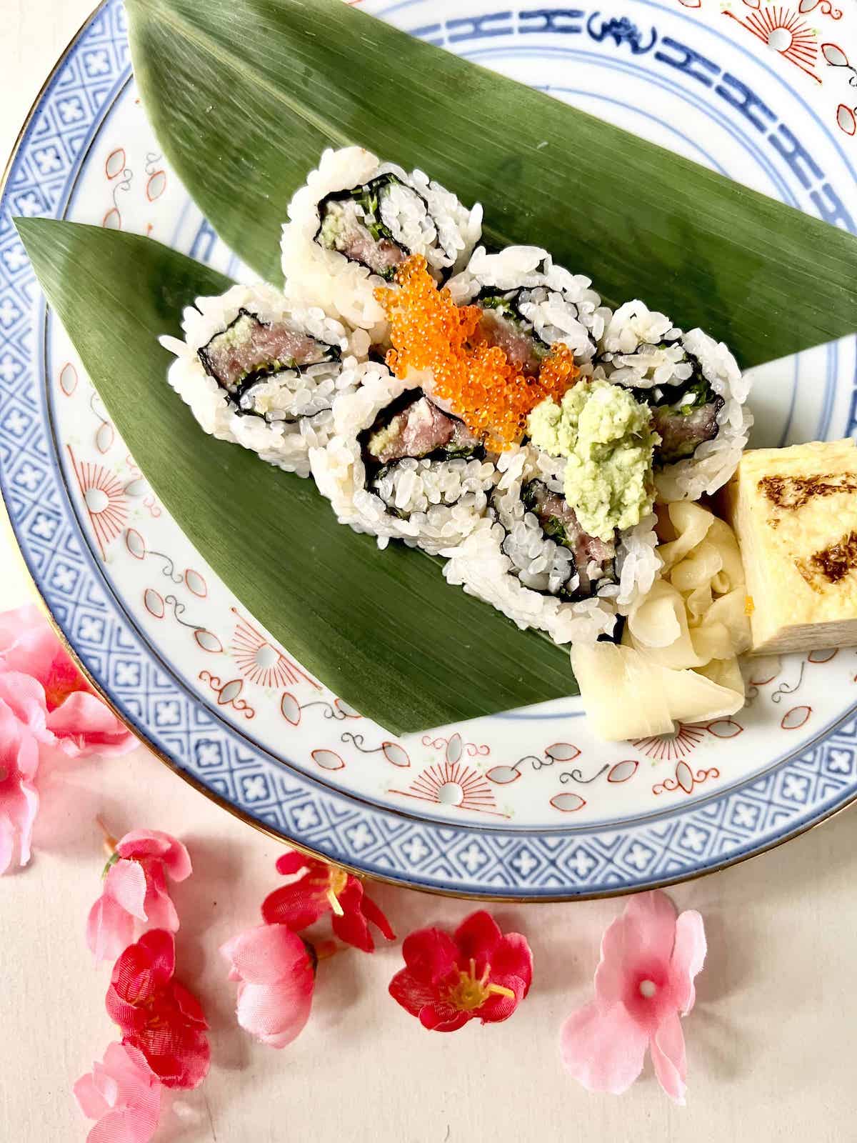 Close-up of tuna maki sushi with wasabi on top and pickled ginger on the side.