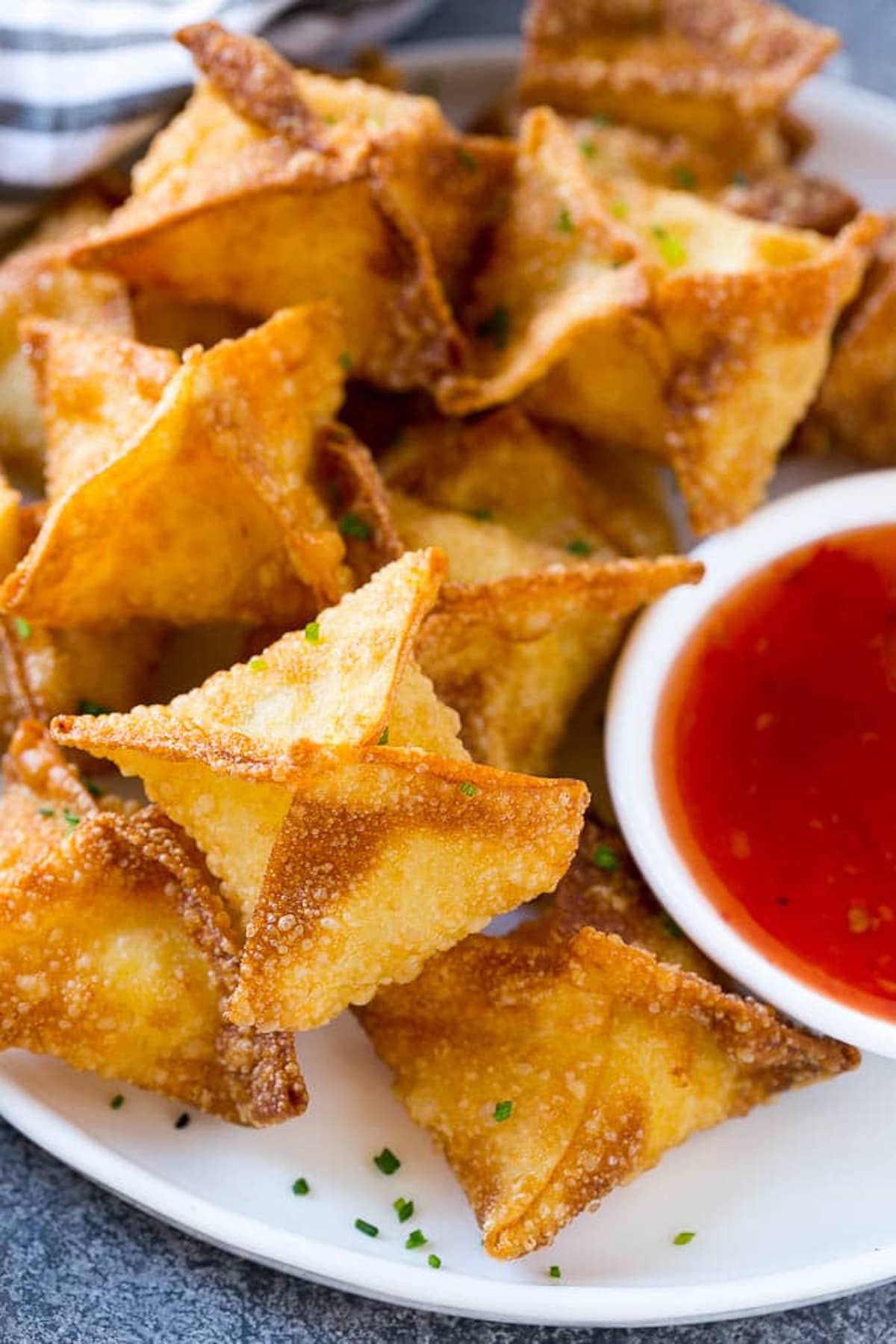 Close-up of golden cream cheese wontons on a white plate.
