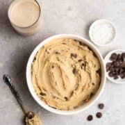 A bowl of sweet cookie dough hummus with condiments around it.