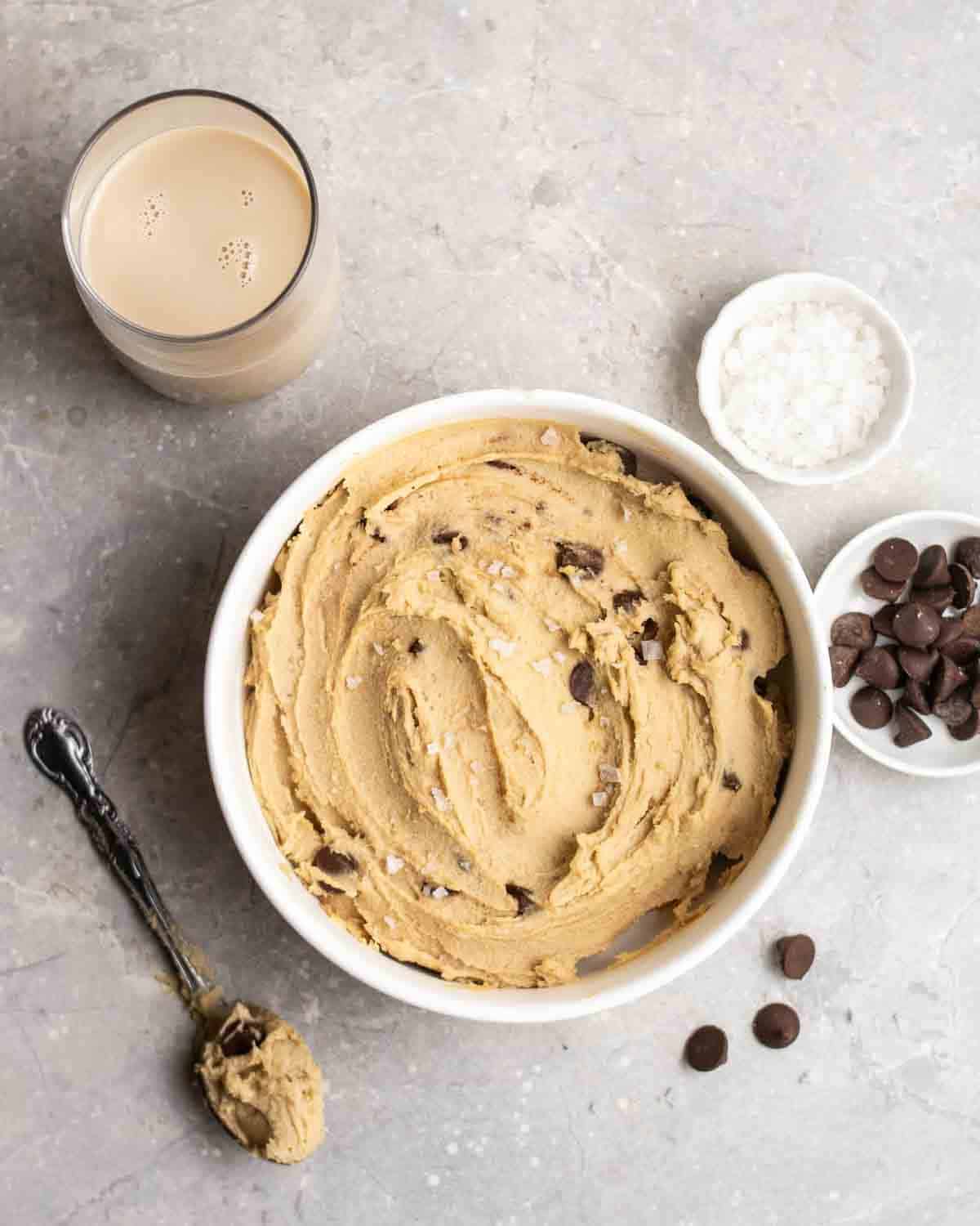 A bowl of sweet cookie dough hummus with condiments around it.
