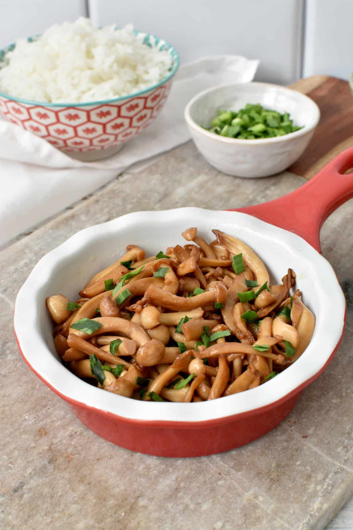 A bowl of stir-fried himeji mushrooms besides white rice.