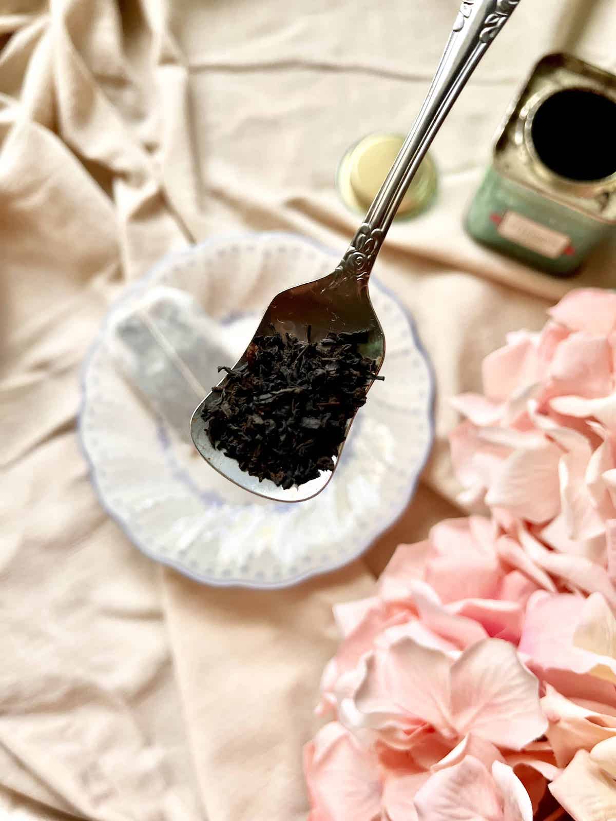 A close-up of black tea leaves with a tea bag in the background.