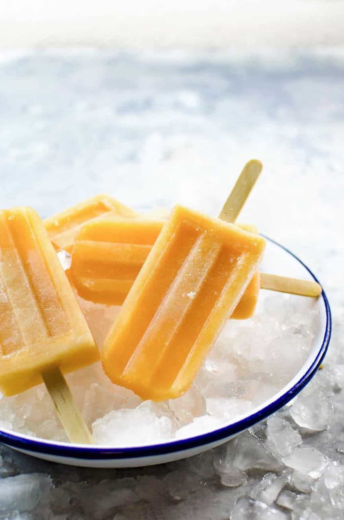 3 lychee ice cream on sticks on top of a bowl of ice.