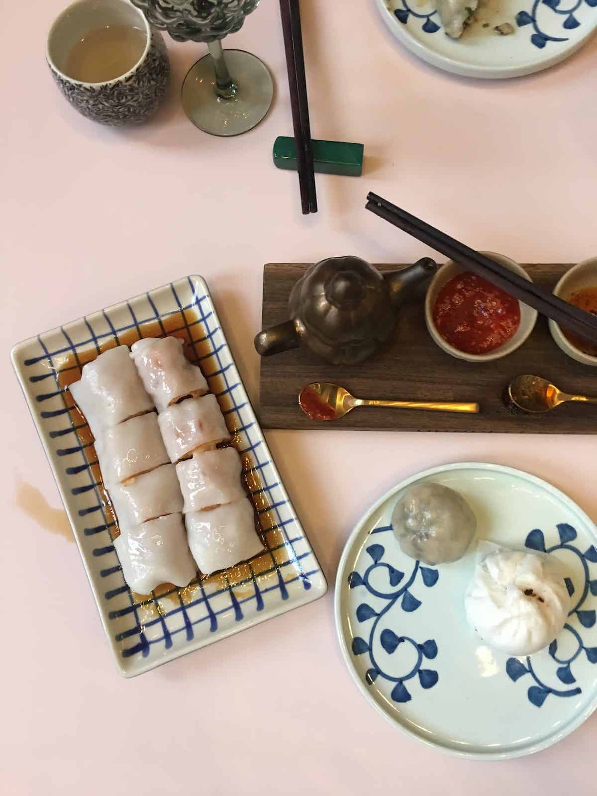 Chee chew fan and char siew bao on a pink dim sum lunch table.