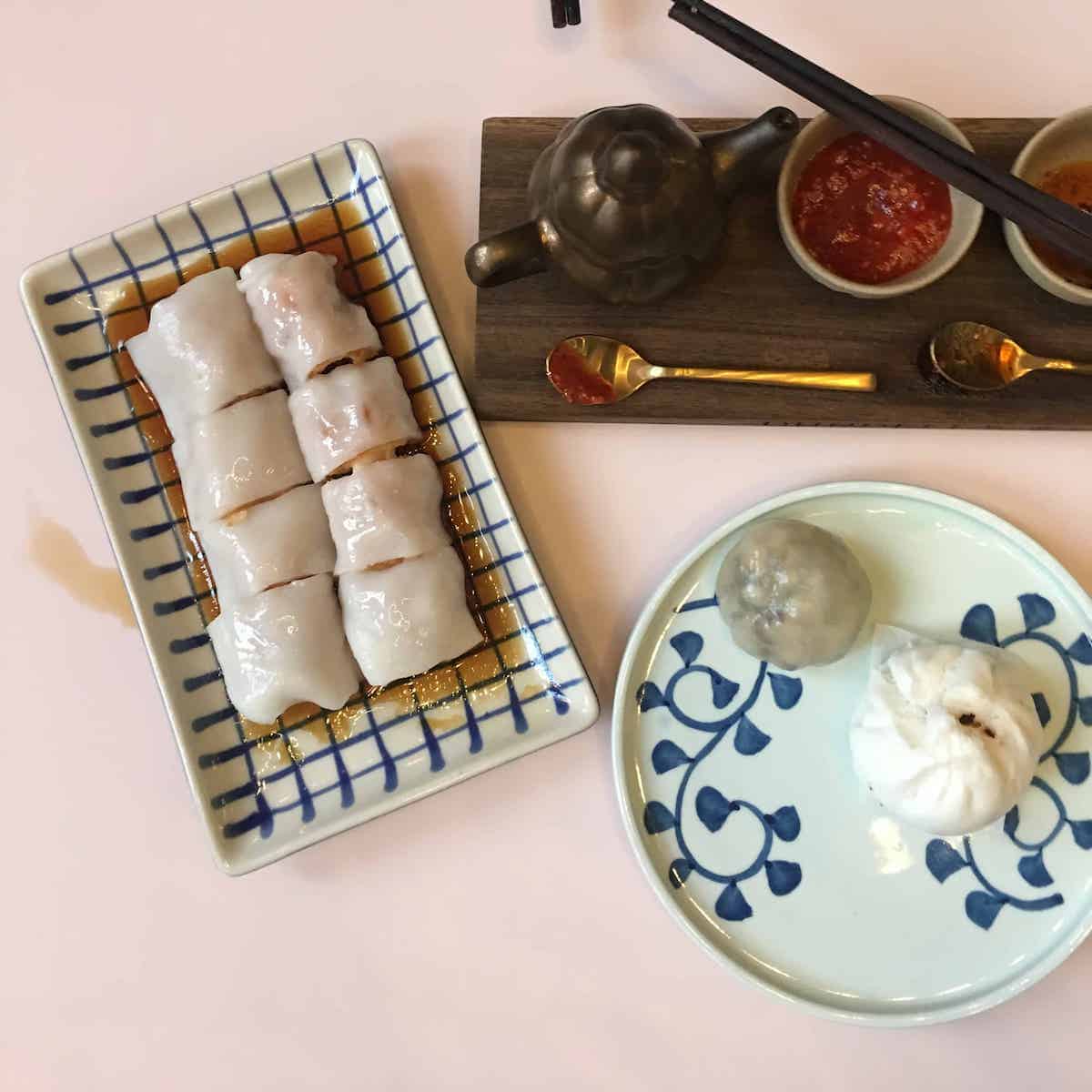 A dim sum spread on a pink table.