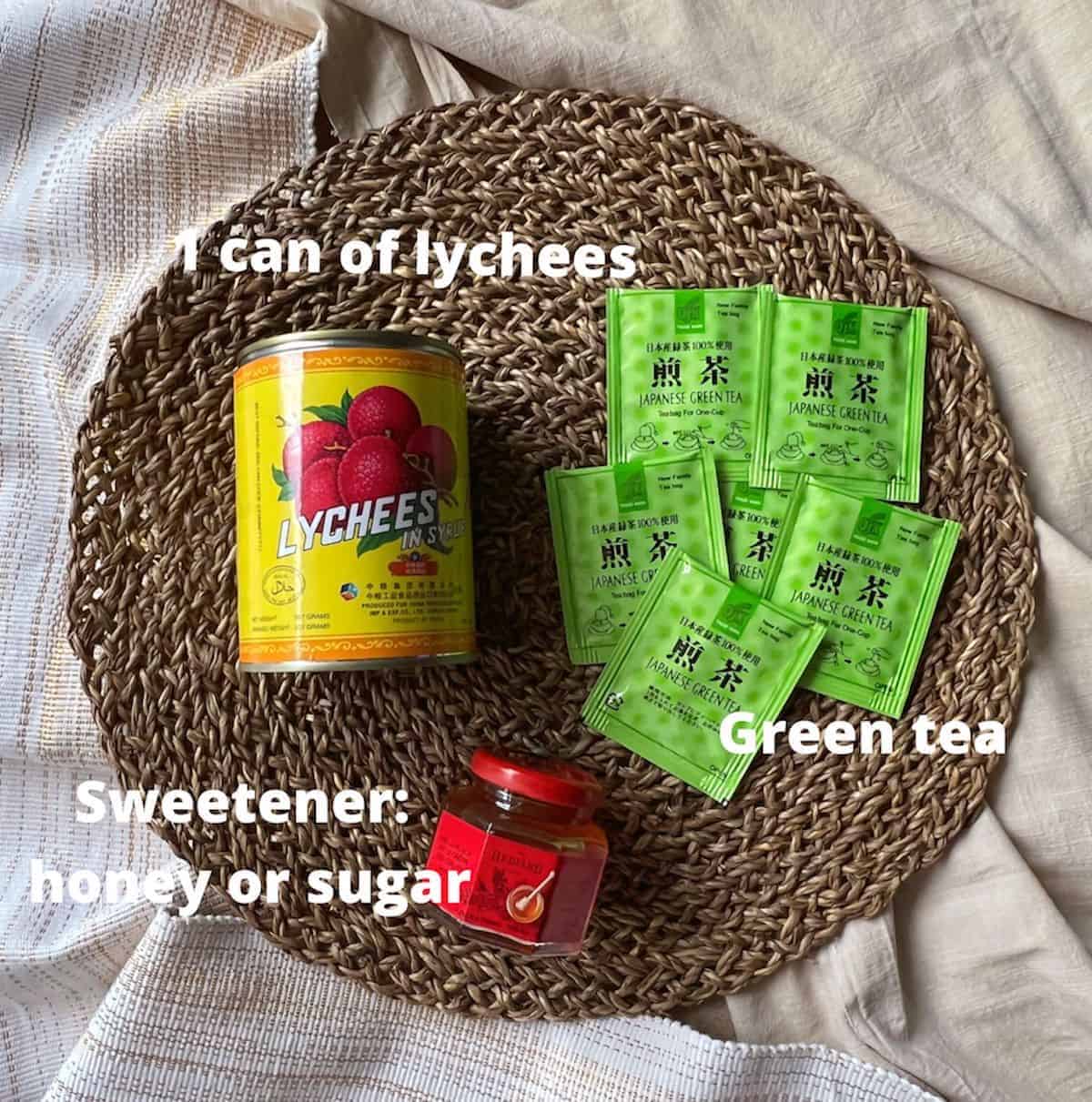 A can of lychees, green tea bags and honey on a placemat.