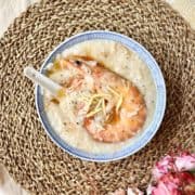 A bowl of seafood congee with prawns and ginger.