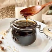 Scooping thick brown sugar syrup out of a glass jar,