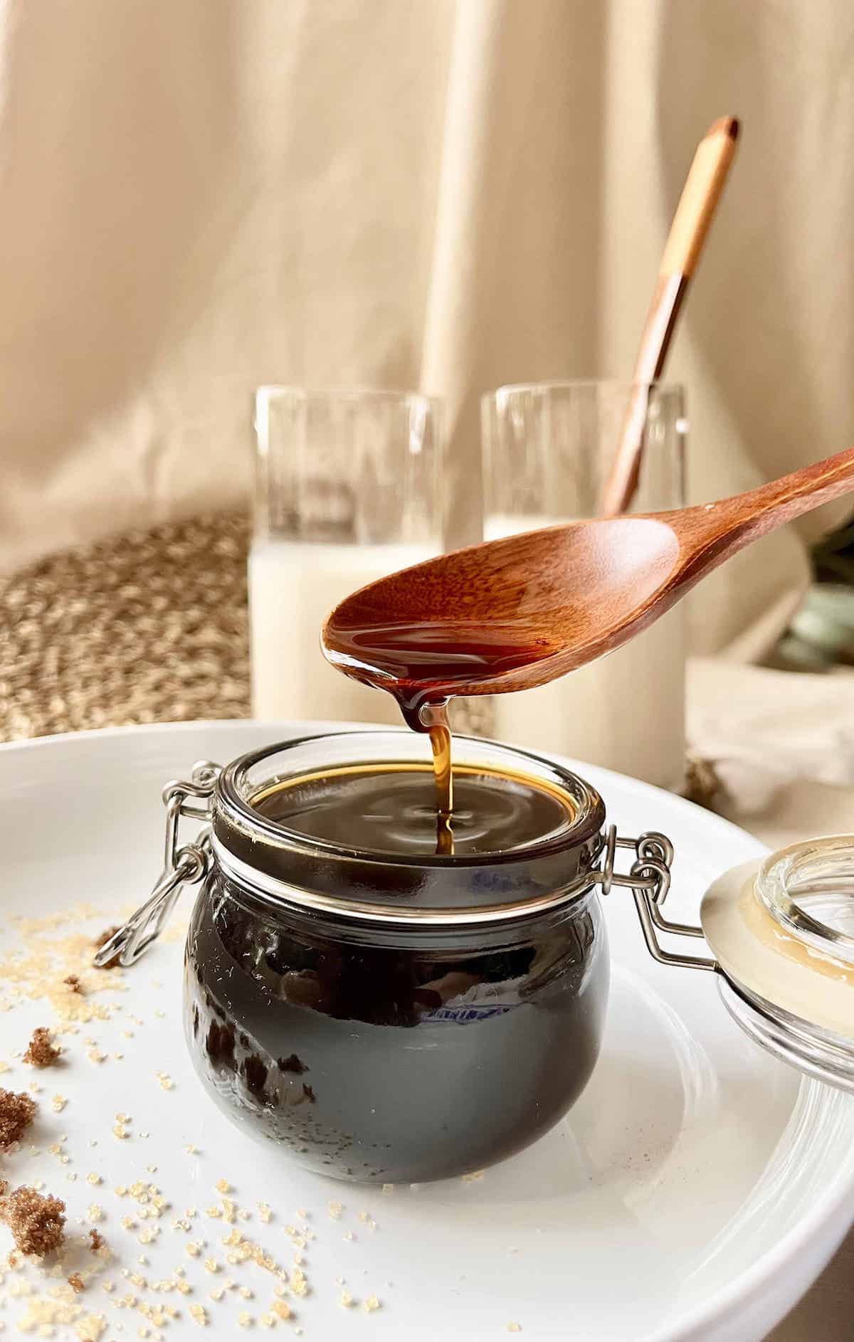 A photo of very thick, unctuous brown sugar syrup slowly dripping off a spoon.