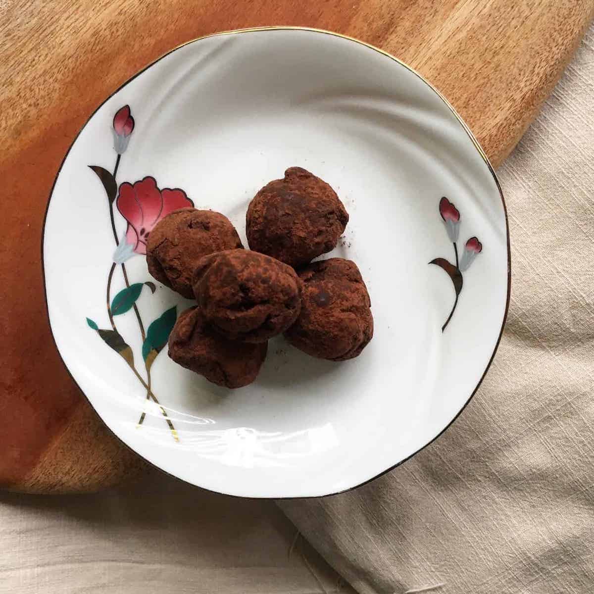 5 handmade round chocolate truffles on a plate.