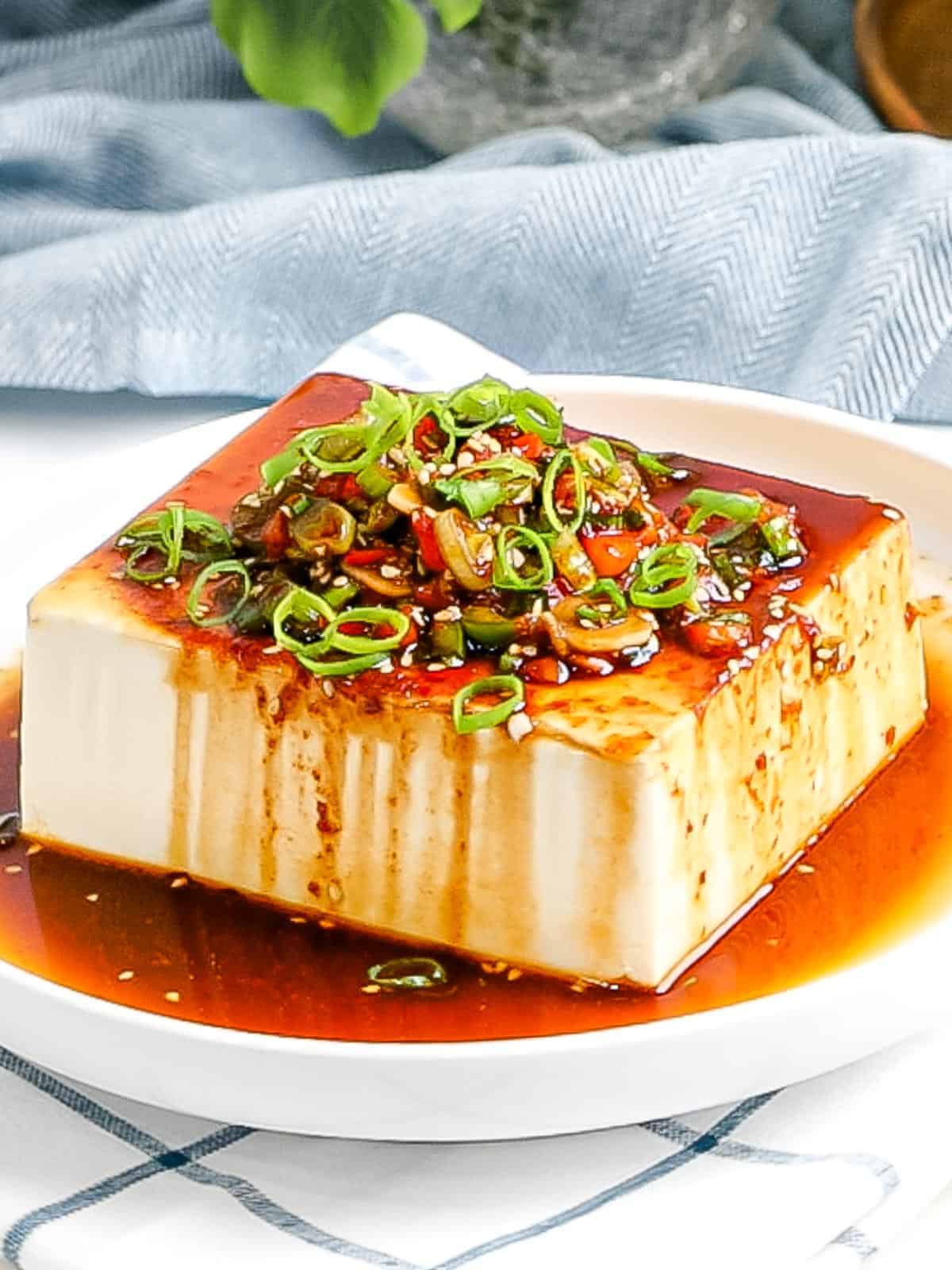 A close-up of a Korean tofu side dish glistening with a soy sauce dressing.