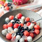 A bowl of round watermelon balls with dragonfruit and berries.