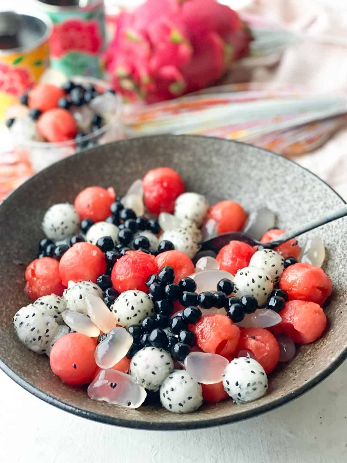 A bowl of round watermelon balls with dragonfruit and berries.