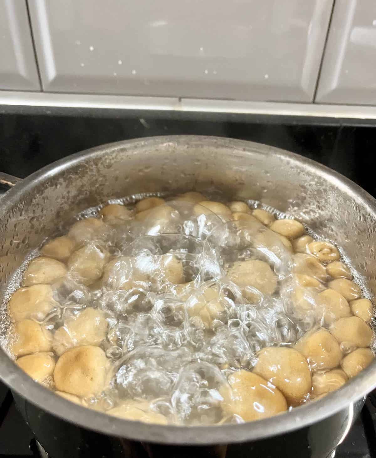 Homemade brown sugar tapioca pearls floating in a pot of boiling water.