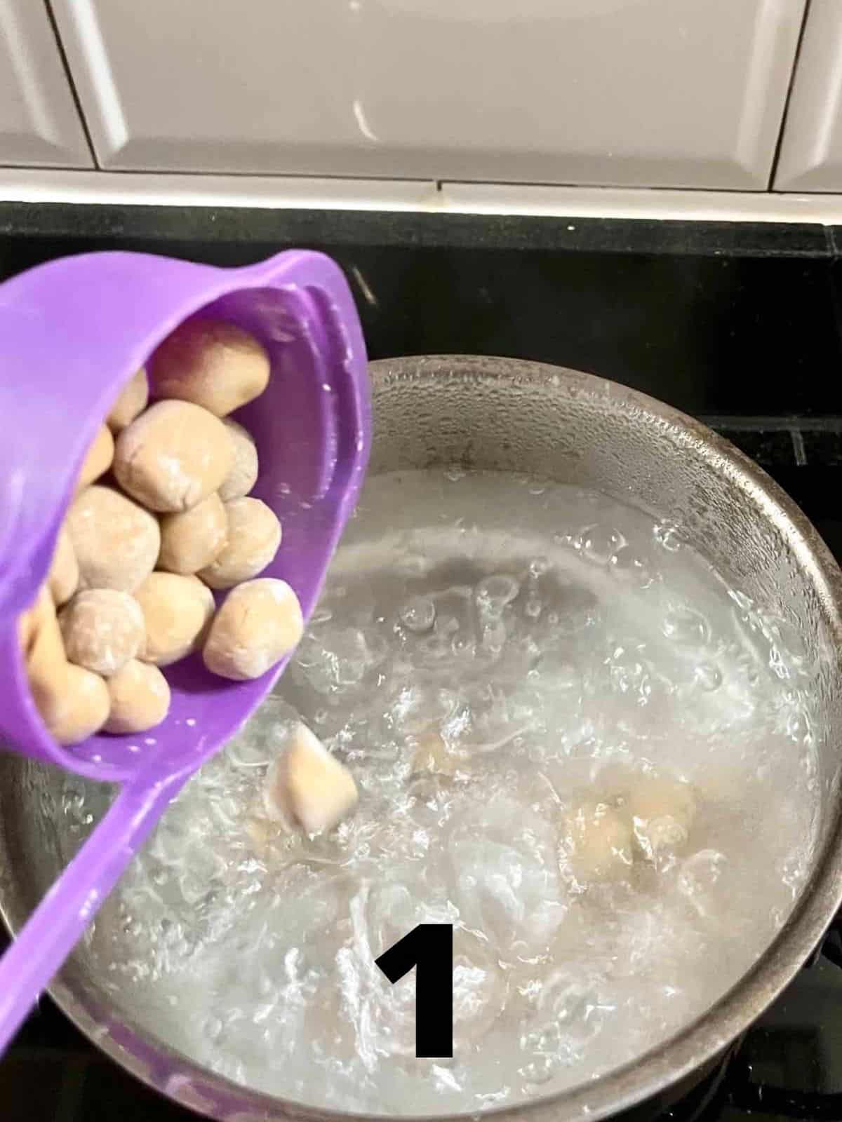 Pouring homemade boba pearls into a boiling pot of water.