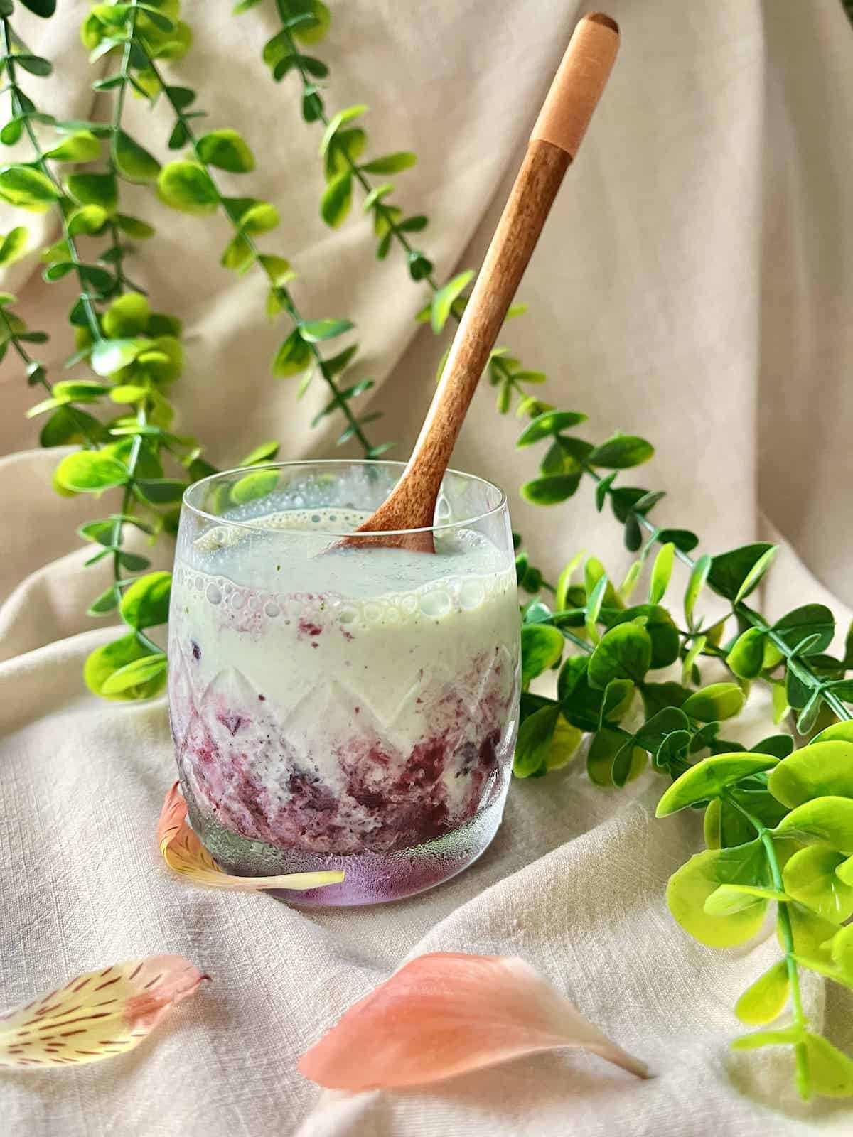 A cup of homemade blueberry matcha latte with a purple swirl through the green drink.