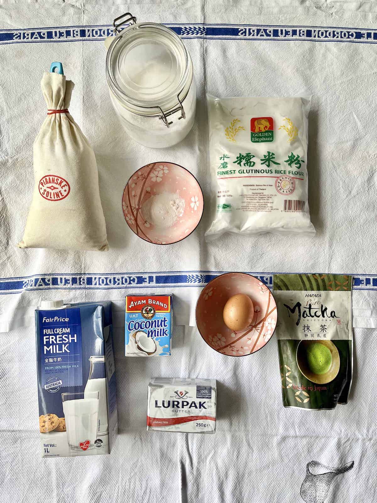 The ingredients needed to make easy matcha mochi cupcakes laid flat on a dishcloth.