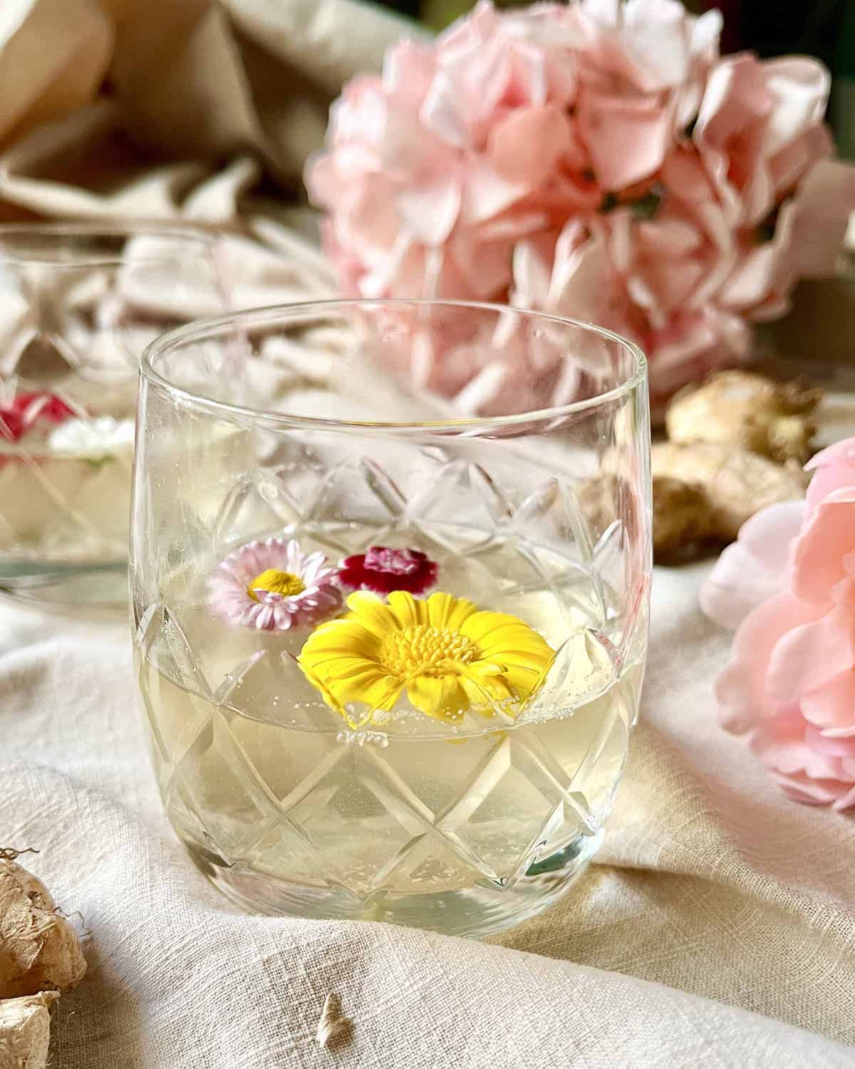 2 glasses of lemongrass tea with flowers floating in them.