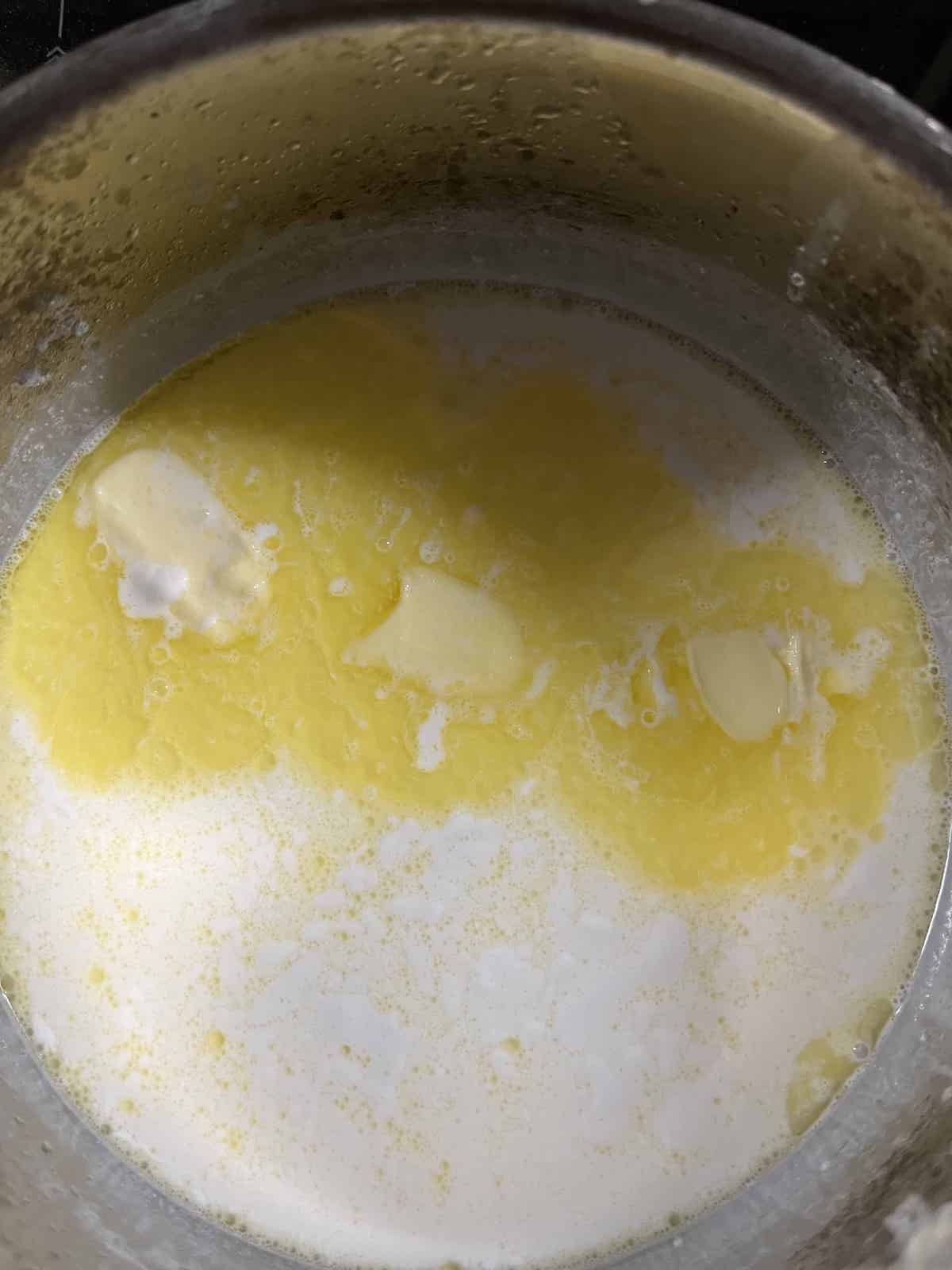 Melting the butter and heating up the milks in a pot.