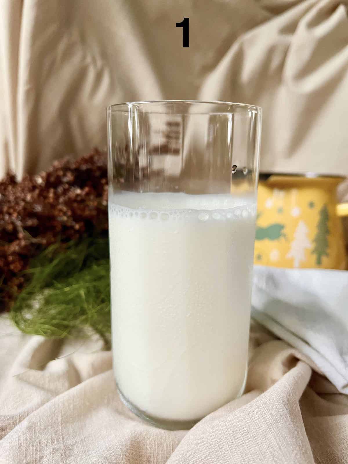 A glass partially filled with milk for hojicha latte.