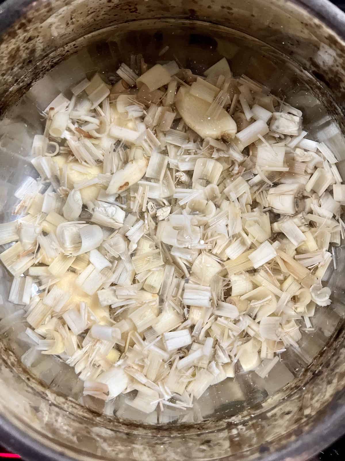 Simmering lemongrass and ginger slices in a pot of water.