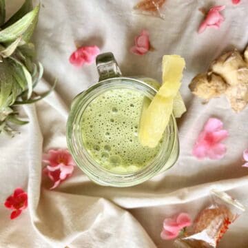 Overhead shot of a glass of pineapple, matcha, ginger and coconut drink.